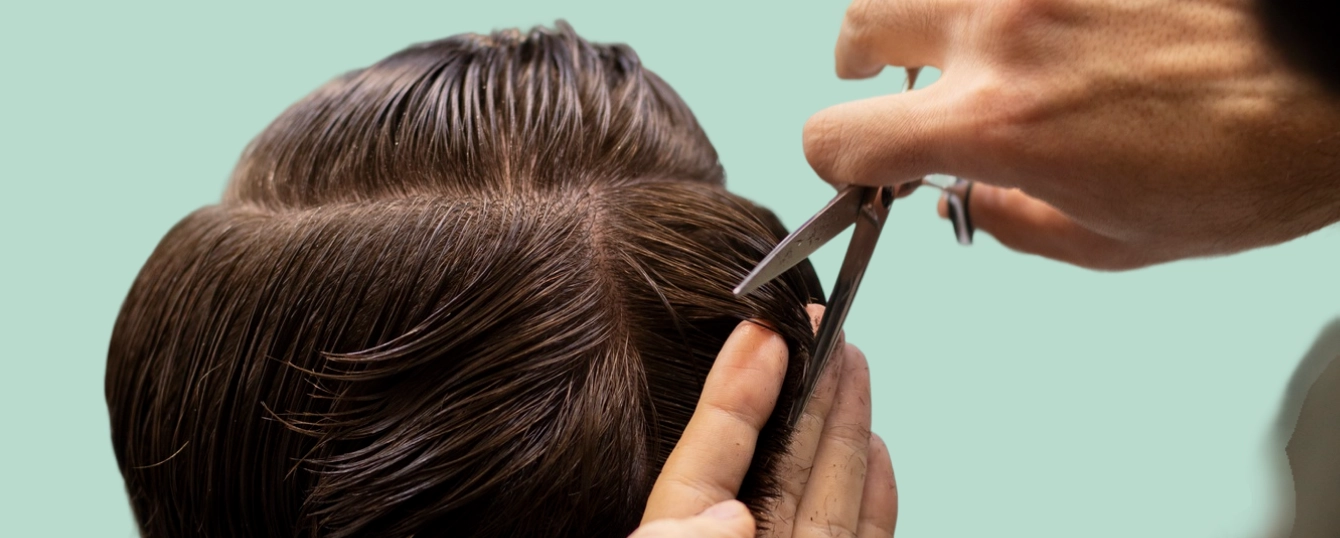 A barber expertly trimming a client's hair with scissors, showing precision and skill in grooming.