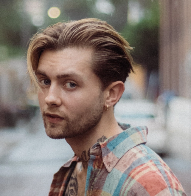 Stylish young man with trendy blonde hairstyle, representing modern barber trends and fashion insights from Eddine Belaid’s Barber Blog.